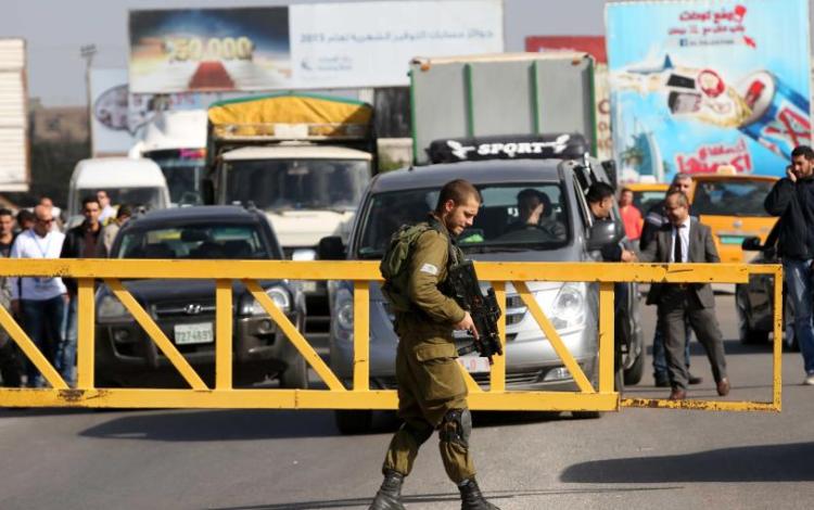 جندي إسرائيلي يقف أمام حاجز عسكري ويمنع مركبات الفلسطينيين من العبور جندي إسرائيلي يقف أمام حاجز عسكري ويمنع مركبات الفلسطينيين من العبور