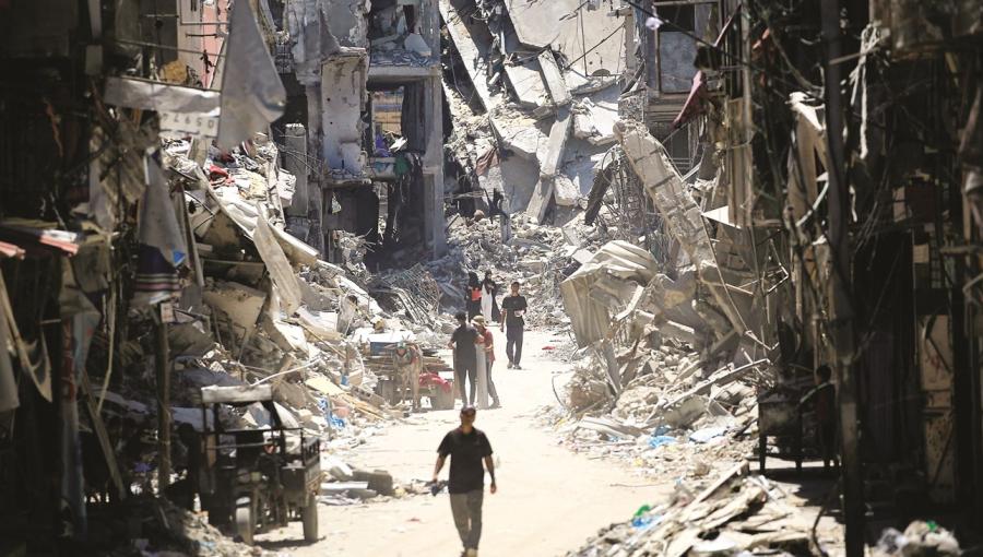 فلسطينيون يسيرون بجوار مبان مدمرة في خانيونس جنوب قطاع غزة فلسطينيون يسيرون بجوار مبان مدمرة في خانيونس جنوب قطاع غزة | المصدر: وكالة الأنباء الفرنسية