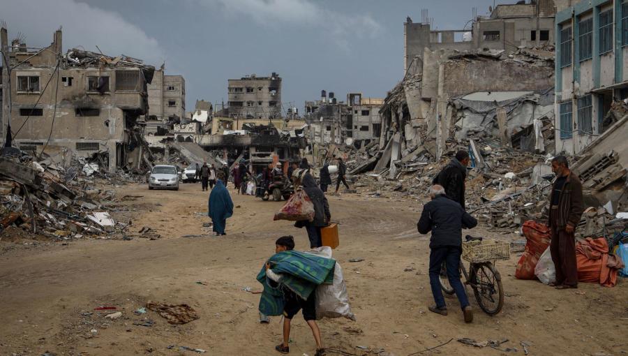 فلسطينيون يسيرون في مدينة خانيونس جنوب قطاع غزة فلسطينيون يسيرون في مدينة خانيونس جنوب قطاع غزة بين مبان مهدمة وهم يحملون متعلقاتهم بحثا عن الأمان| المصدر: الأمم المتحدة