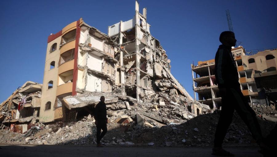 فلسطينيون يسيرون في حي دمره الاحتلال في مخيم النصيرات للاجئين وسط قطاع غزة فلسطينيون يسيرون في حي دمره الاحتلال في مخيم النصيرات للاجئين وسط قطاع غزة | المصدر: وكالة الأنباء الفرنسية