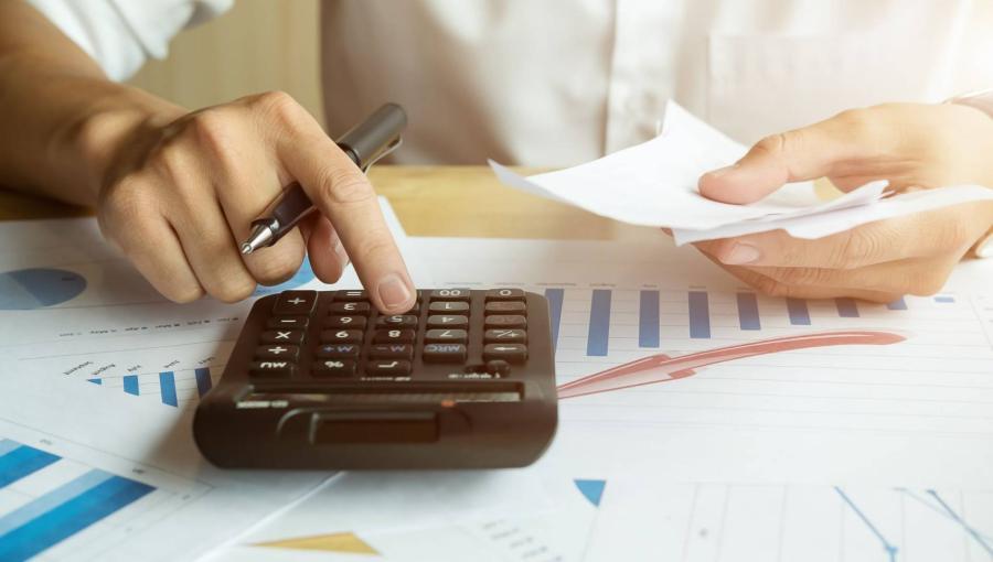 شخص يجري عملية حسابية على آلة حاسبة | تعبيرية