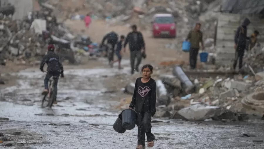 طفلة تحمل دلوين خاليين في طريقها لجلب المياه وسط أمطار غزيرة على حي الشيخ رضوان بمدينة غزة 15/11/2025 | أسوشييتد برس