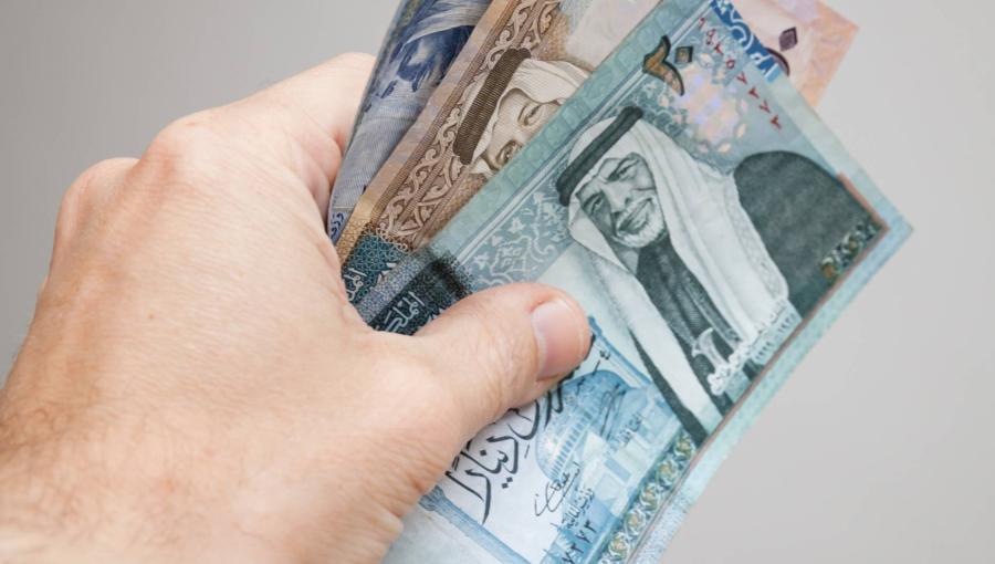 يد تمسك عدة أوراق نقدية أردنية من فئات مختلفة | تعبيرية