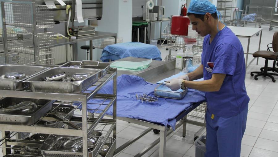 عامل طبي يرتدي لباسا واقيا يقوم بترتيب وتعقيم أدوات جراحية في مستشفى | تعبيرية