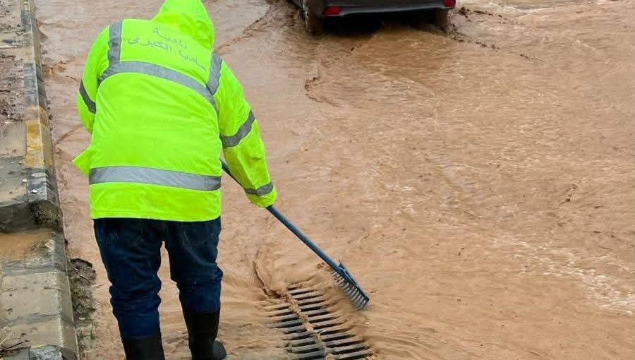 أحد كوادر بلدية مأدبا يعمل على تصريف مياه أمطار غمرت أحد الشوارع إثر هطولات مطرية غزيرة | أرشيفية