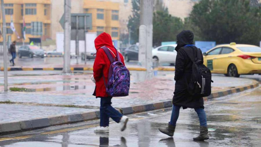 طفلان يعبران أحد شوارع العاصمة عمان في أجواء باردة وماطرة خلال منخفض جوي | أرشيفية