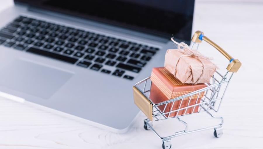 عربة تسوق صغيرة بجانب حاسوب محمول | تعبيرية freepik