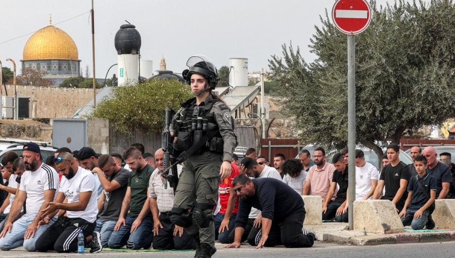 مجندة من جيش الاحتلال تمر بجانب المصلين أثناء صلاة الجمعة | أرشيفية