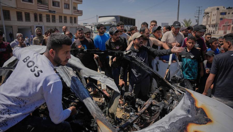 فلسطينيون يتفقدون مركبة استهدفت بغارة جوية إسرائيلية في دير البلح وسط قطاع غزة | أسوشييتد برس