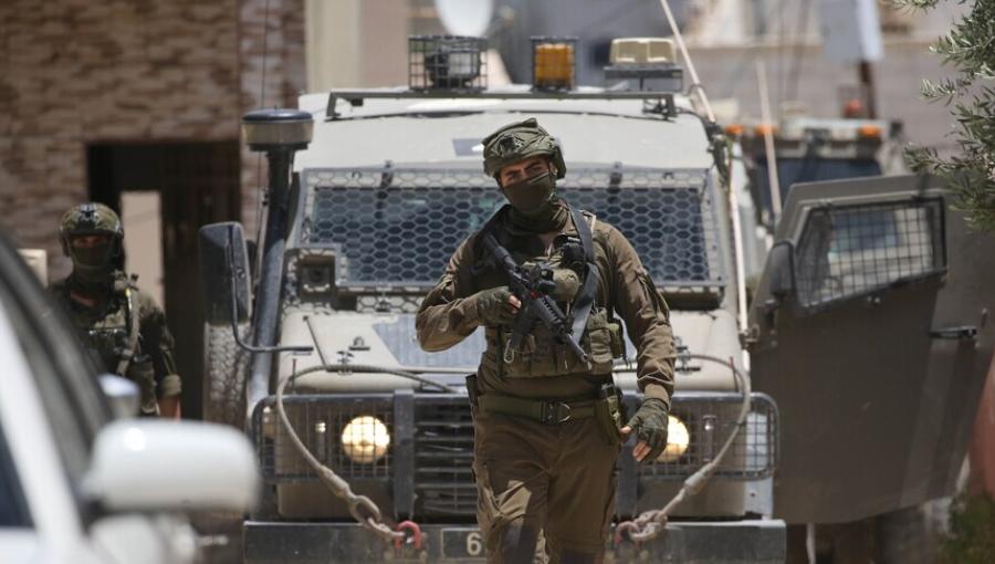 أحد جنود الاحتلال يقف بالقرب من مدرعة عسكرية في الضفة الغربية | الأناضول