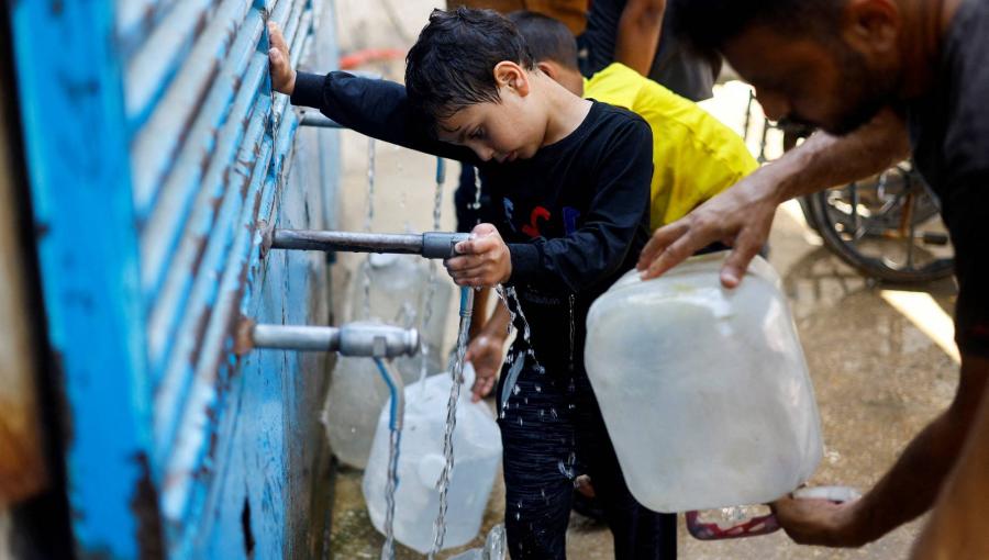 فلسطينيون يملؤون عبوات المياه في نقطة توزيع مياه بالنصيرات وسط قطاع غزة | رويترز