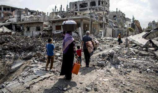 عائلة غزّية تمشي على ركام منزلها المدمّر جراء العدوان الاسرائيلي أيار 2021