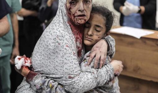 أم فلسطينية مغطاة بالدماء تحتضن ابنتها بعد أن نجا كلاهما من هجوم جوي إسرائيلي في غزة