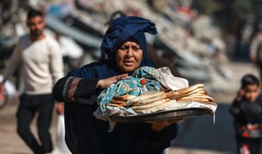 فلسطينية تحمل الخبز خارج مدرسة تابعة للأمم المتحدة في غزة | المصدر: فرانس برس