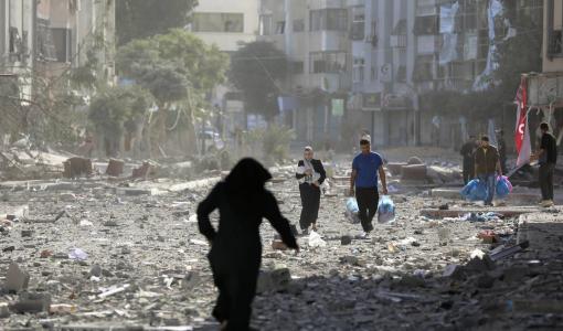 فلسطينيون يسيرون وسط دمار خلّفه القصف الإسرائيلي في غزة