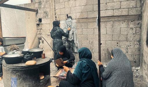 فتاة فلسطينية ترسم على جدران مركز إيواء في دير البلح رسمات تجسد معاناة النازحين | المصدر: فلسطين بوست