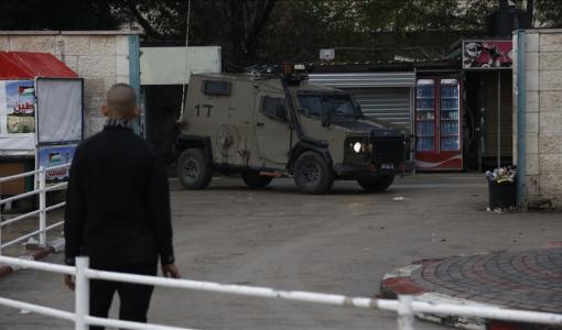 فلسطيني يقف بالقرب من آلية لجيش الاحتلال خلال اقتحام سابق في الضفة الغربية | المصدر: الأناضول