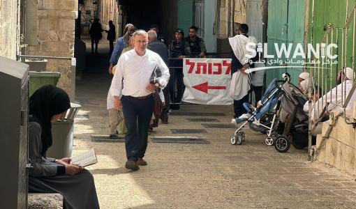 مستوطنون يخرجون عبر باب السلسلة بعد اقتحامهم للمسجد الأقصى في أول أيام عيد الفصح العبري وعلى اليسار تجلس سيدة تقرأ القرآن وسط منع المصلين من الدخول إلى المسجد الأقصى 23/4/2024 | المصدر: مركز معلومات وادي حلوة