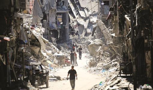 فلسطينيون يسيرون بجوار مبان مدمرة في خانيونس جنوب قطاع غزة فلسطينيون يسيرون بجوار مبان مدمرة في خانيونس جنوب قطاع غزة | المصدر: وكالة الأنباء الفرنسية