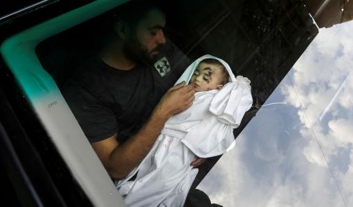 فلسطيني يحمل طفلا استشهد جراء العدوان الإسرائيلي على غزة