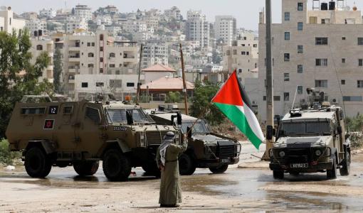 فلسطيني يلوح بعلم فلسطين بمواجهة آليات عسكرية إسرائيلية في طولكرم 22/8/2024 | المصدر: رويترز