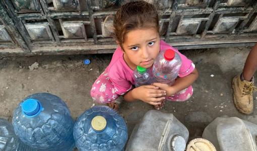 طفلة تنتظر دورها لتعبئة المياه في غزة | المصدر: منظمة الأمم المتحدة