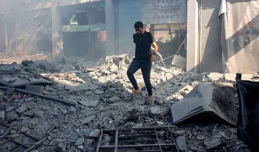 شاب فلسطيني يسير بين أنقاض مبنى تعرض لقصف إسرائيلي في حي الشيخ رضوان بغزة | المصدر: وكالة الأنباء الفرنسية