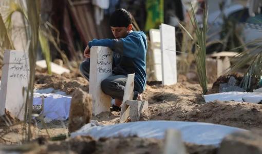 طفل غزي يجلس قرب قبر أحد أقربائه الذين استشهدوا إثر قصف الاحتلال على غزة | المصدر: middleeasteye