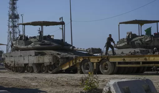 جنود إسرائيليون يرفعون دبابة على شاحنة نقل على الحدود مع قطاع غزة 18/1/2025 | المصدر: أسوشييتد برس