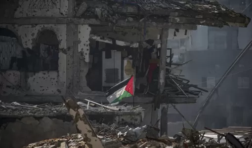 علم فلسطيني يرفرف بجوار مأوى لأسرة فلسطينية بين أنقاض المباني المدمرة في مخيم جباليا للاجئين شمال قطاع غزة 17/2/2025 | المصدر: وكالة الأنباء الفرنسية