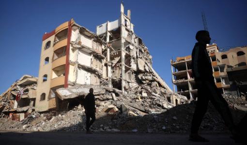 فلسطينيون يسيرون في حي دمره الاحتلال في مخيم النصيرات للاجئين وسط قطاع غزة | المصدر: وكالة الأنباء الفرنسية