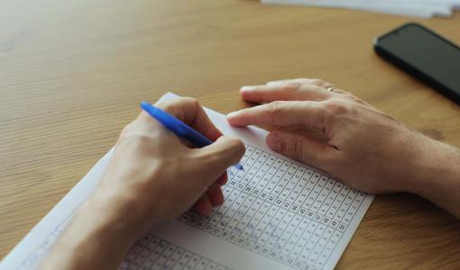 يد تمسك ورقة وقلم | تعبيرية freepik