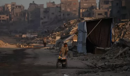 فلسطينيون يسيرون بين الدمار الذي خلفته الغارات الجوية والأرضية الإسرائيلية في حي الشيخ رضوان في مدينة غزة | أسوشييتد برس