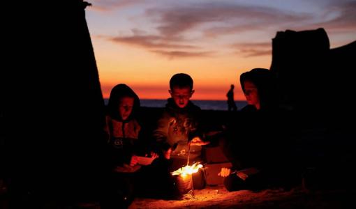 أطفال فلسطينيون يتحلقون حول النار طلبا للدفء وسط قطاع غزة 17/11/2025 | المصدر: رويترز