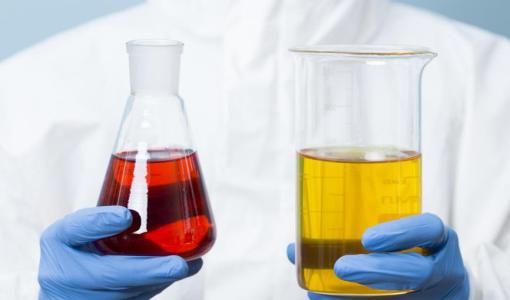 اختصاصي كيمياء يحمل زجاجتين لمواد كيميائية | تعبيرية Freepik