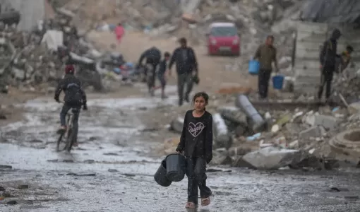 طفلة تحمل دلوين خاليين في طريقها لجلب المياه وسط أمطار غزيرة على حي الشيخ رضوان بمدينة غزة 15/11/2025 | أسوشييتد برس