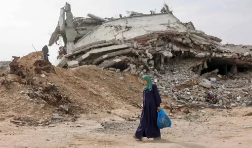 فلسطينية نازحة تمر أمام مبنى مدمر في حي تل الهوى جنوب مدينة غزة 29/11/2025 | وكالة الأنباء الفرنسية