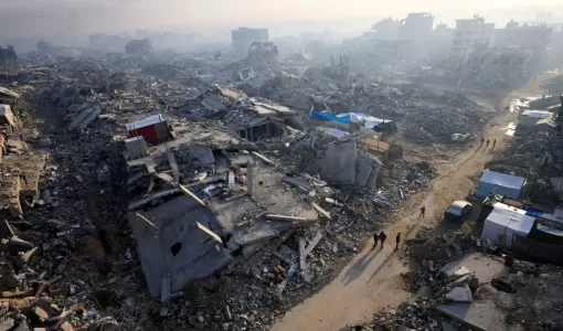 فلسطينيون يسيرون بين أنقاض المباني المدمرة بسبب غارات الاحتلال على مدينة غزة | رويترز