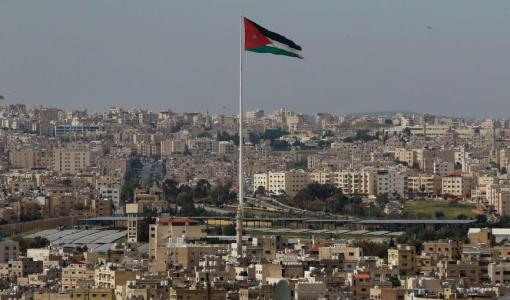 مشهد لمدينة عمان يتوسط المشهد سارية علم ترفع العلم الأردني