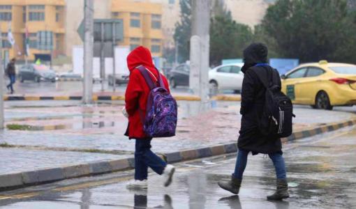 طفلان يعبران أحد شوارع العاصمة عمان في أجواء باردة وماطرة خلال منخفض جوي | أرشيفية