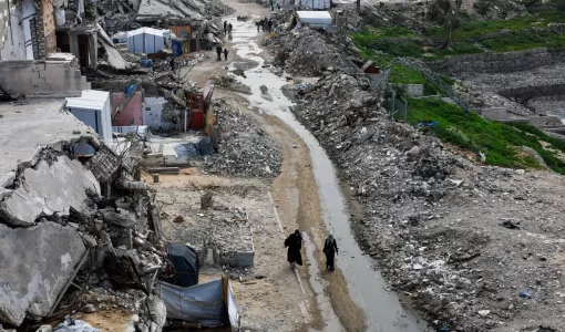 فلسطينيون يسيرون بين أنقاض المباني السكنية التي دمرتها حرب الإبادة الإسرائيلية في مدينة غزة 28/1/2026 | رويترز