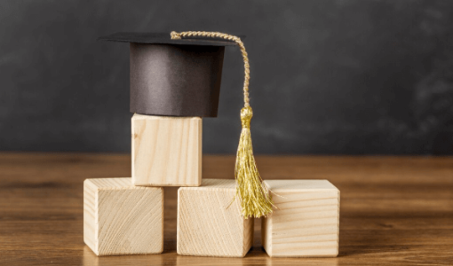 قبعة تخرج فوق مكعبات خشبية | تعبيرية freepik