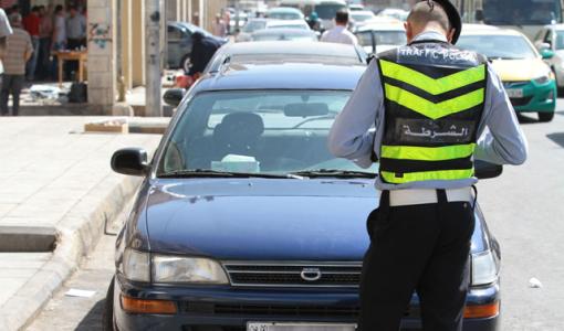 أحد مرتبات شرطة السير وهو يحرر مخالفة لسيارة في أحد شوارع العاصمة عمان | أرشيفية jordantimes