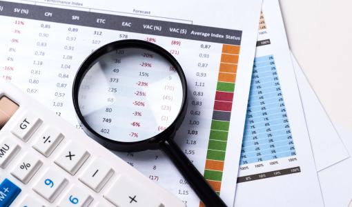 عدسة مكبرة فوق أوراق بجانبها آلة حاسبة | تعبيرية freepik