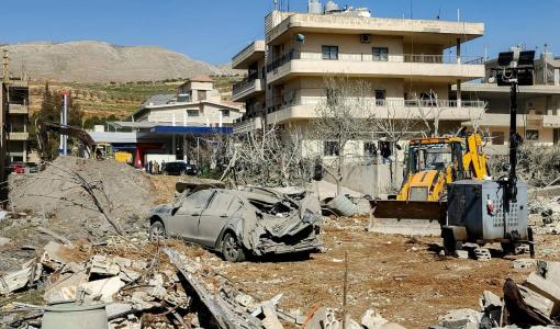 جرافة تزيل الأنقاض بالقرب من مبانٍ متضررة بشدة بقرية بدنايل بمنطقة سهل البقاع الشرقية في لبنان | وكالة الأنباء الفرنسية