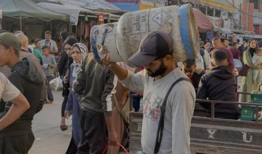 فلسطيني يحمل على كتفه أسطوانة غاز | وكالة الأنباء الفرنسية