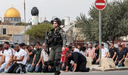 مجندة من جيش الاحتلال تمر بجانب المصلين أثناء صلاة الجمعة | أرشيفية