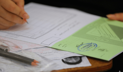 طالب يدون إجاباته في ورقة امتحان توجيهي