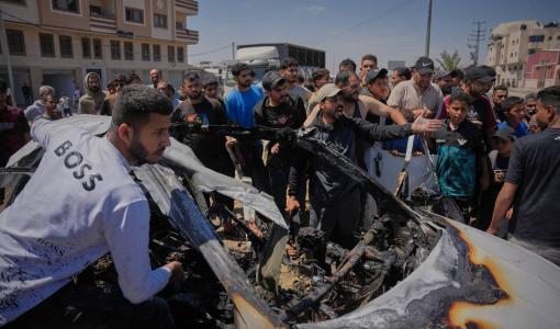 فلسطينيون يتفقدون مركبة استهدفت بغارة جوية إسرائيلية في دير البلح وسط قطاع غزة | أسوشييتد برس