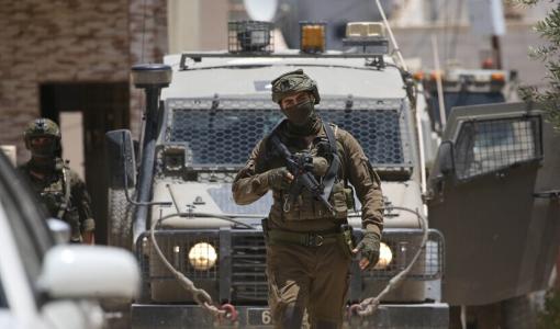أحد جنود الاحتلال يقف بالقرب من مدرعة عسكرية في الضفة الغربية | الأناضول